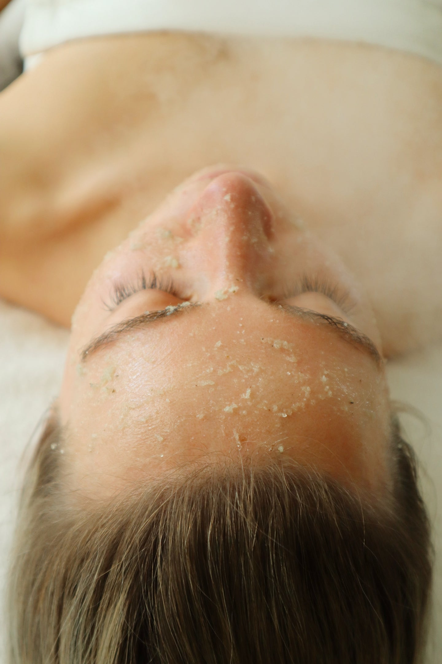 Woman receiving exfoliating skin care treatment with facial scrub at Bella Santé spa in Boston