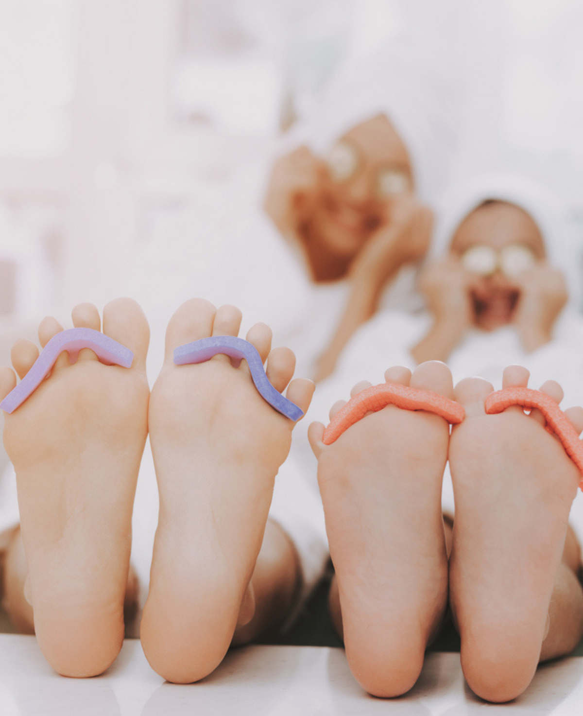 Two guests enjoying side-by-side pedicures with colorful gel polish as part of a couples spa package at Bella Santé in Boston.