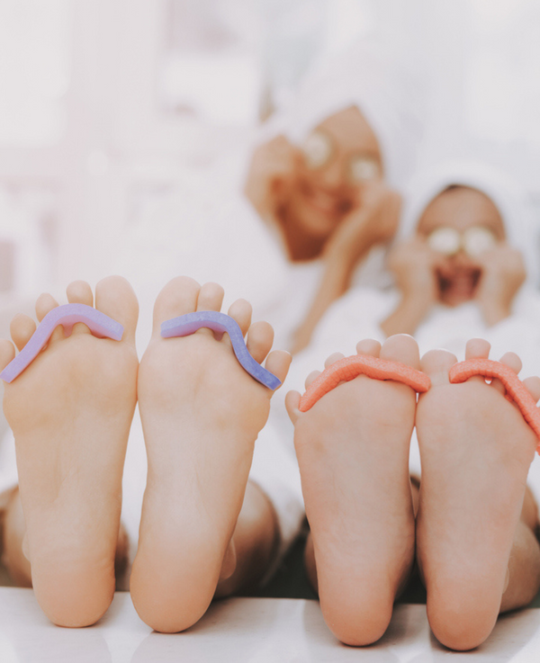 Two guests enjoying side-by-side pedicures with colorful gel polish as part of a couples spa package at Bella Santé in Boston.