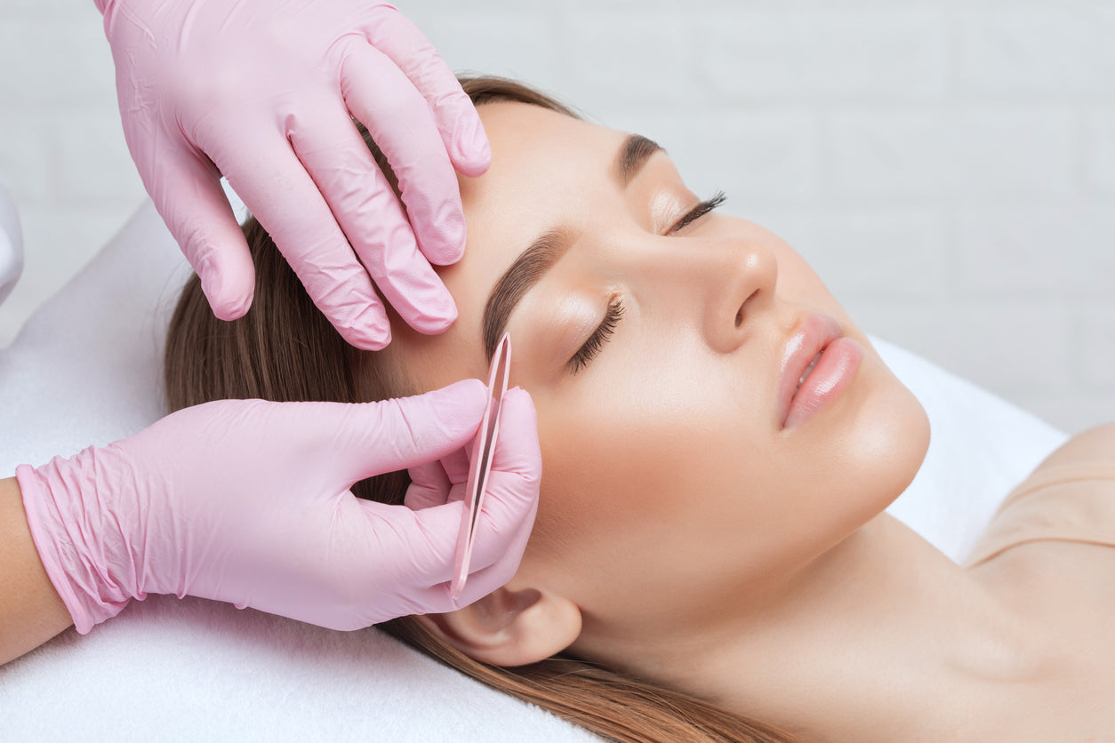 Woman receiving professional eyebrow shaping and tweezing at Bella Santé Spa in Boston, Lexington, and Wellesley