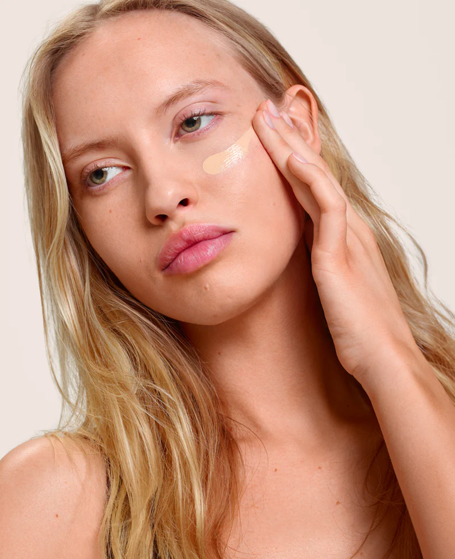 Woman applying facial cream as part of a summer skin care routine