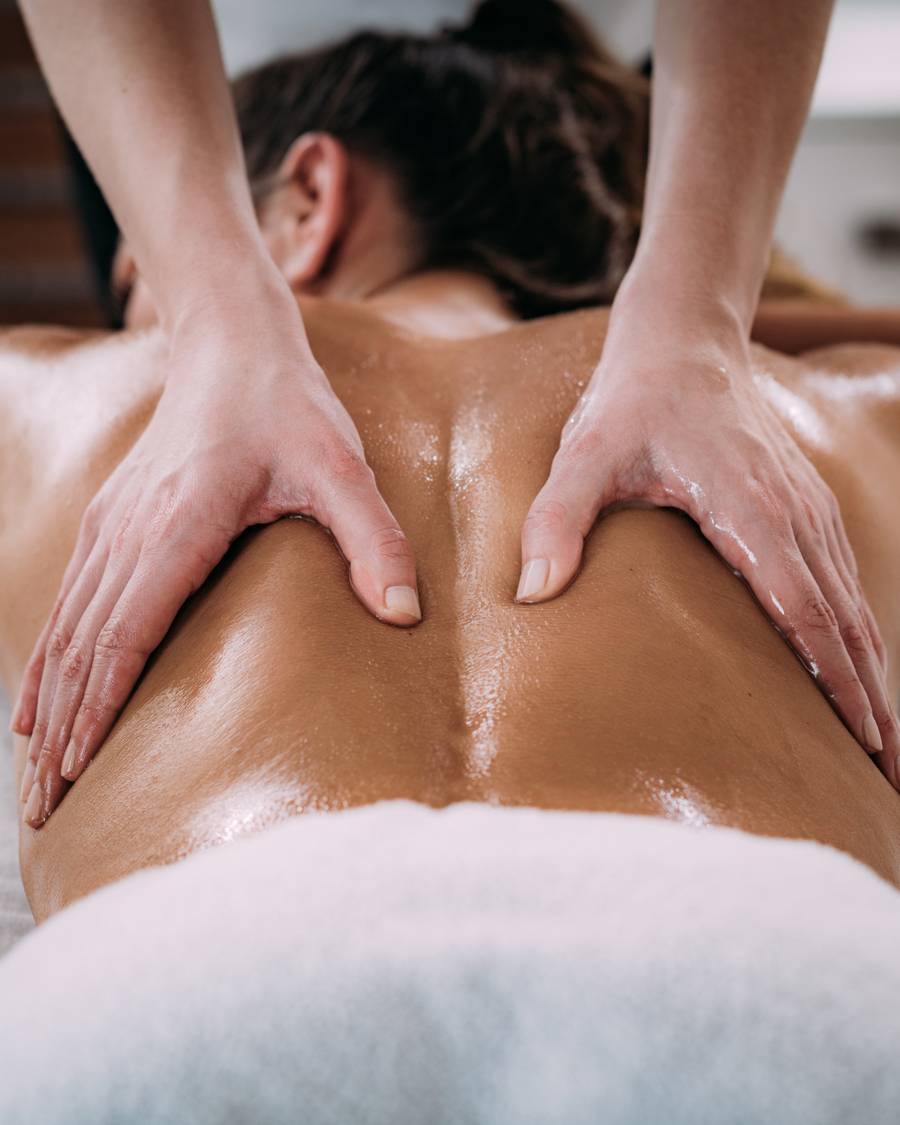 Woman with two hands on her back receiving a massage at our Best of Boston Spa available in Boston, Lexington and Wellesley.