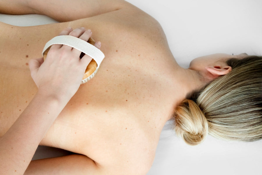 Person using a dry body brush on the back to promote smoother skin and boost surface circulation