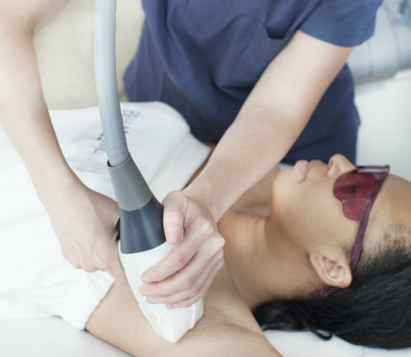 Woman with a darker skin tone receiving underarm laser hair removal treatment