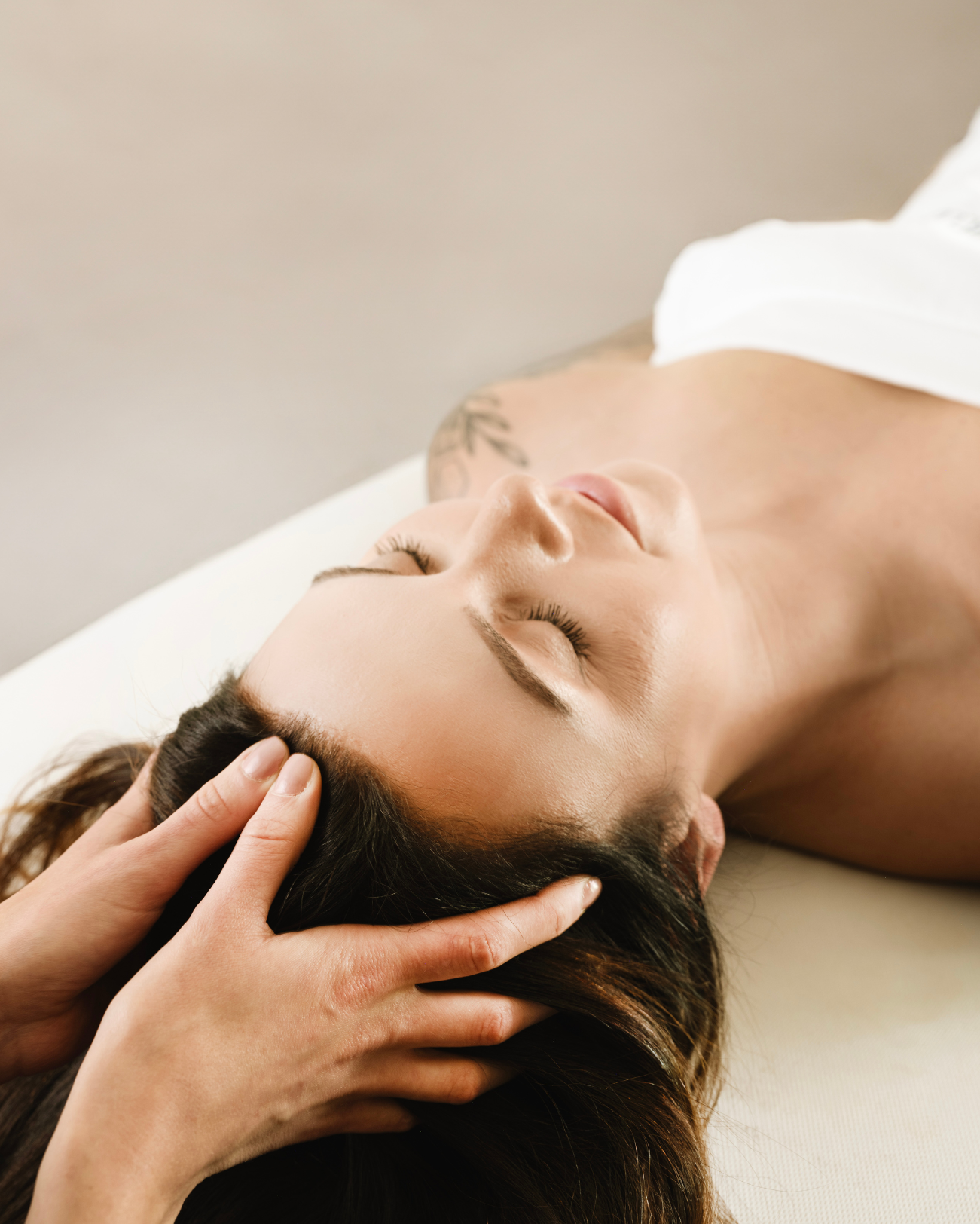 Woman relaxing on a spa treatment table with a towel wrap during a professional med spa treatment service at a luxury day spa.