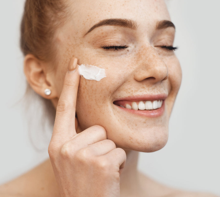 Redheaded woman applying face cream as part of her daily skincare routine