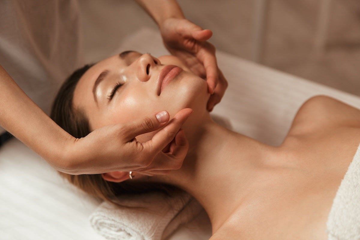 A person receiving a sculpting facial in Boston with a focus on the upper body and facial massage being performed by a professional.