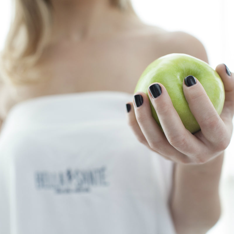 Woman from neck down only wearing spa towel holding apple after having Best of Boston OPI gel manicure at Bella Sante Spa in Boston, Lexington and Wellesley