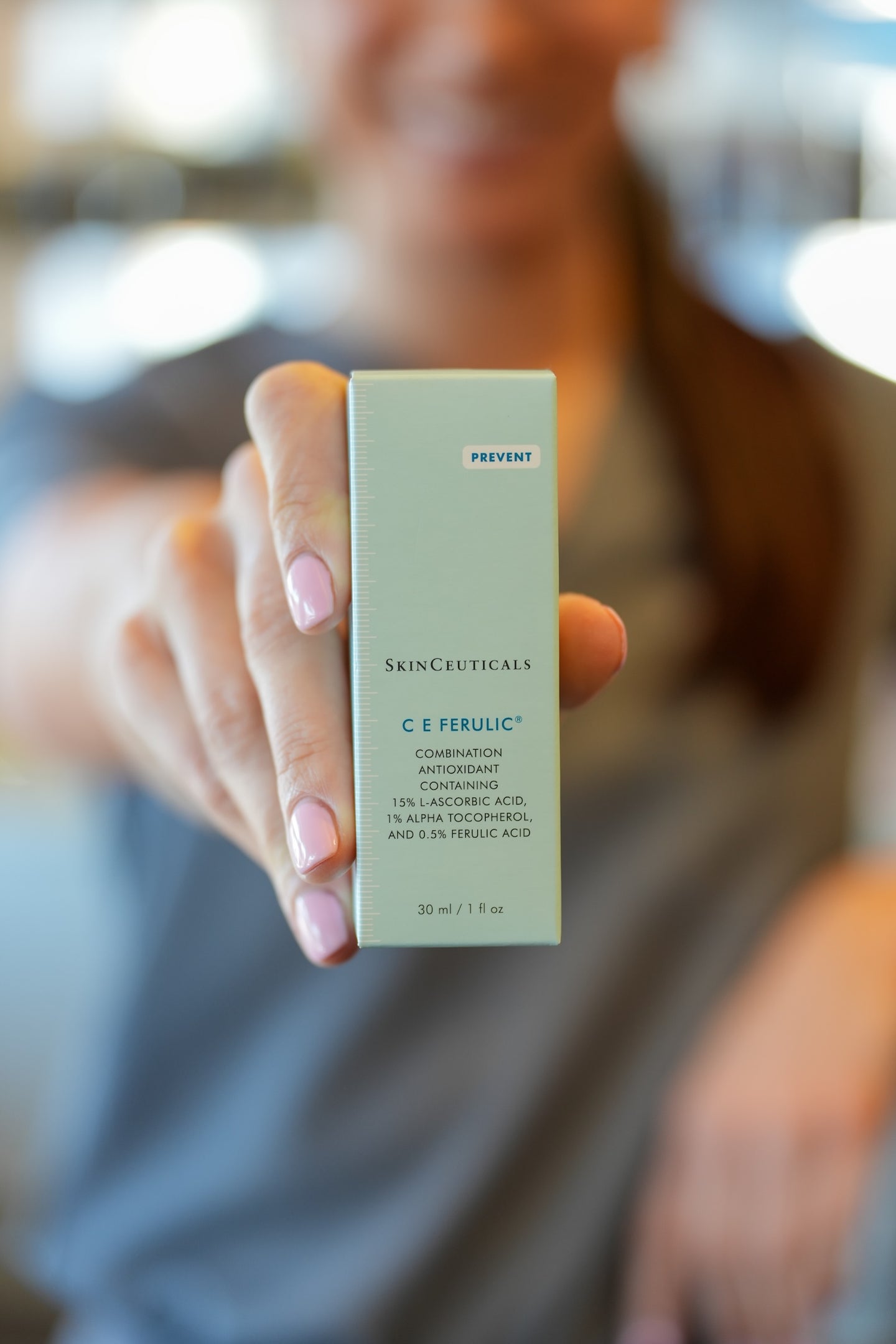 Person holding a Skinceuticals C E Ferulic skincare product box.