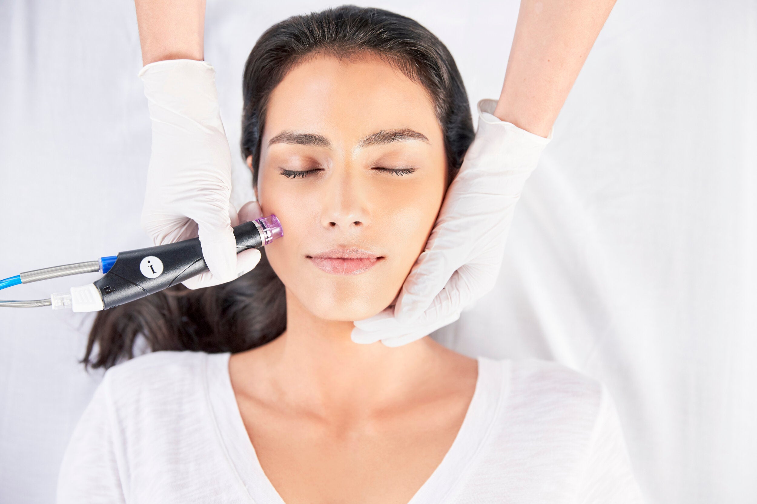 Image of a woman on a table face up receiving a HydraFacial. Click on link to go to navigate to the Best of Boston facial menu.