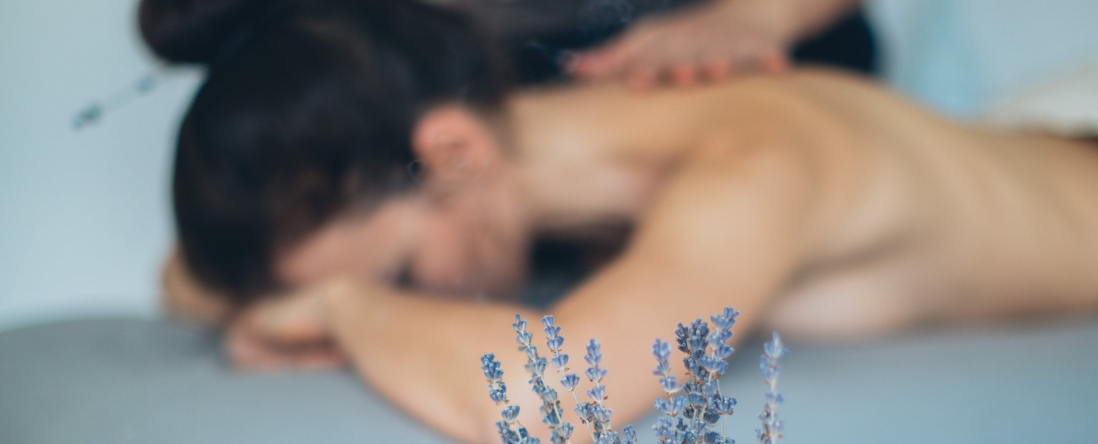 Image of of a woman on a table face down receving a massage. Lavender in the foreground. Click on link to go to navigate to the Best of Boston massage menu.
